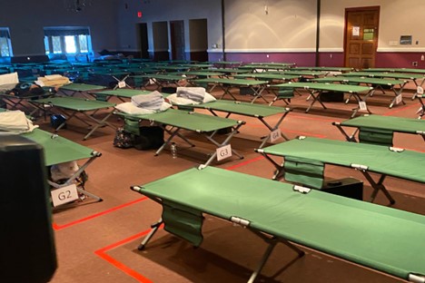 Rows of numbered cots lined up in a large room